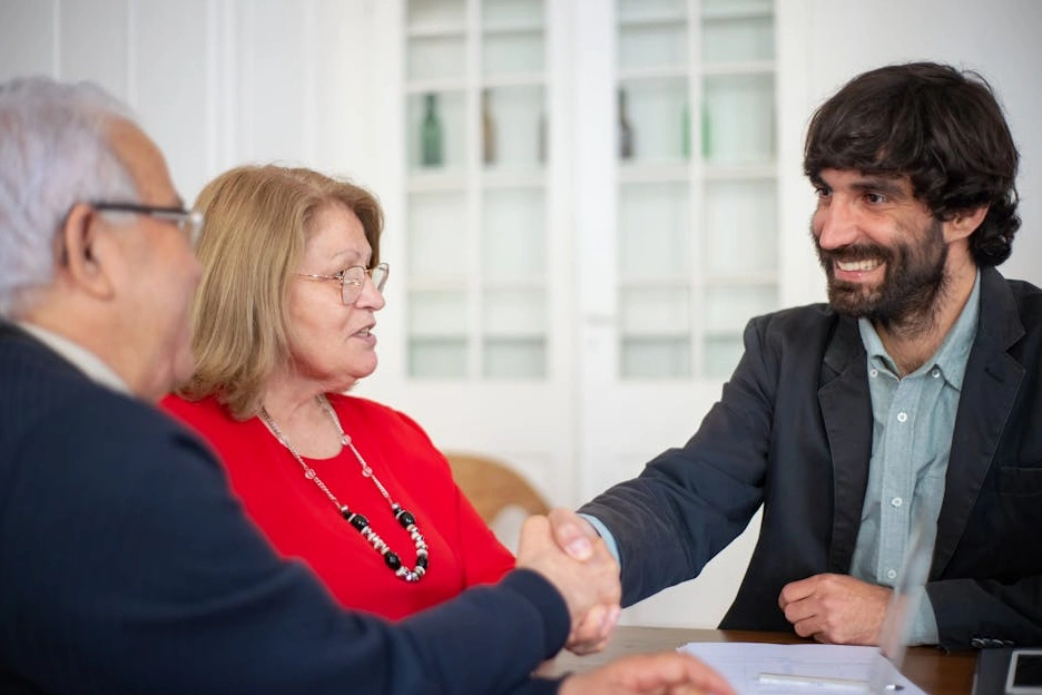 A consultant shaking hands with a client across a desk.
